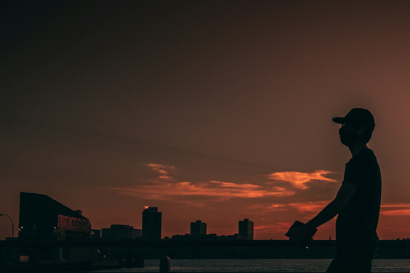 A person silhouetted against an orange evening sky.